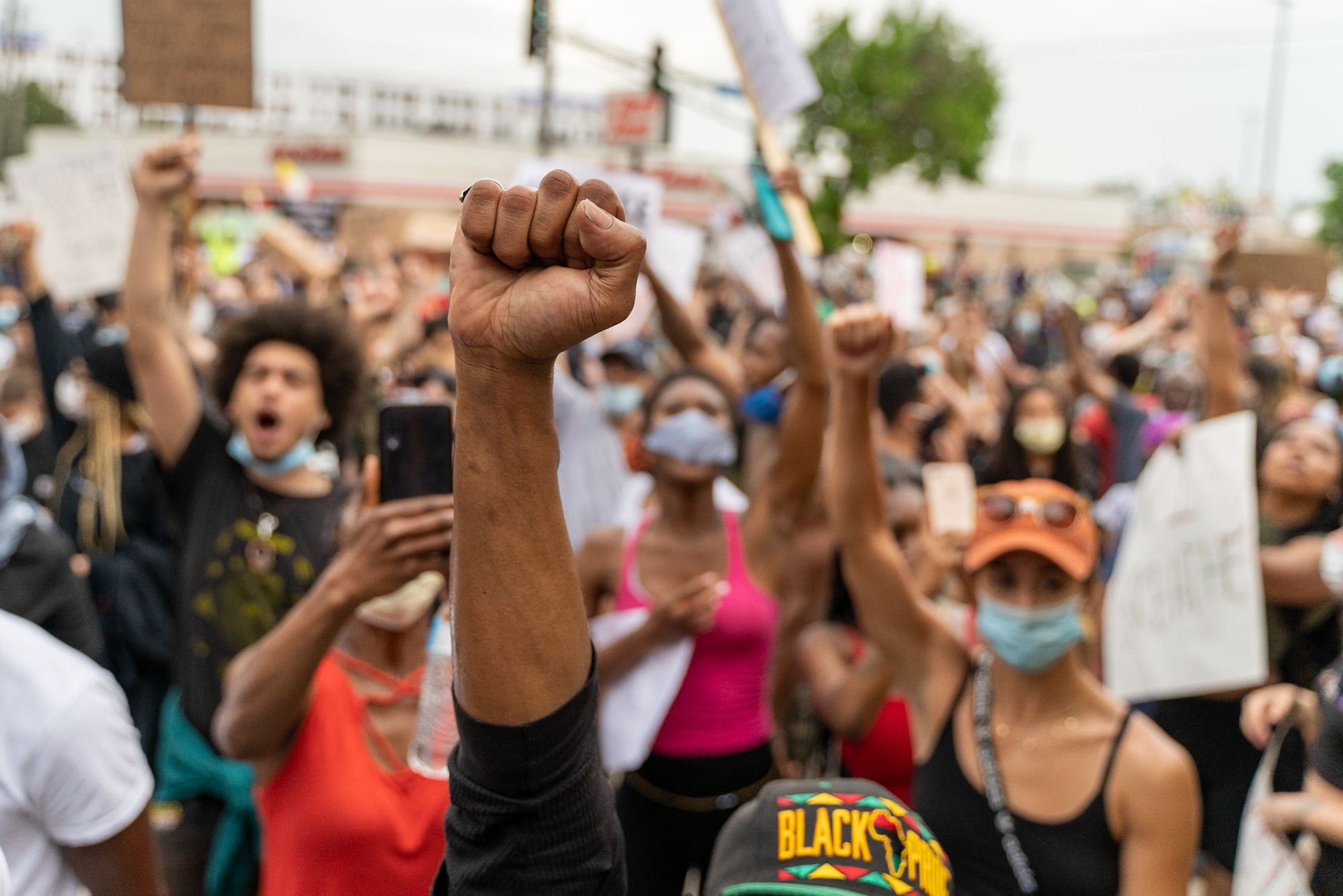 Image of the raised and clenched fists of a large group of protestors demanding Justice for George Floyd